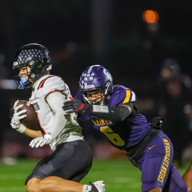 Huntington Beach’s Troy Foster carries the ball as Crean Lutheran’s Javari Nash pursues