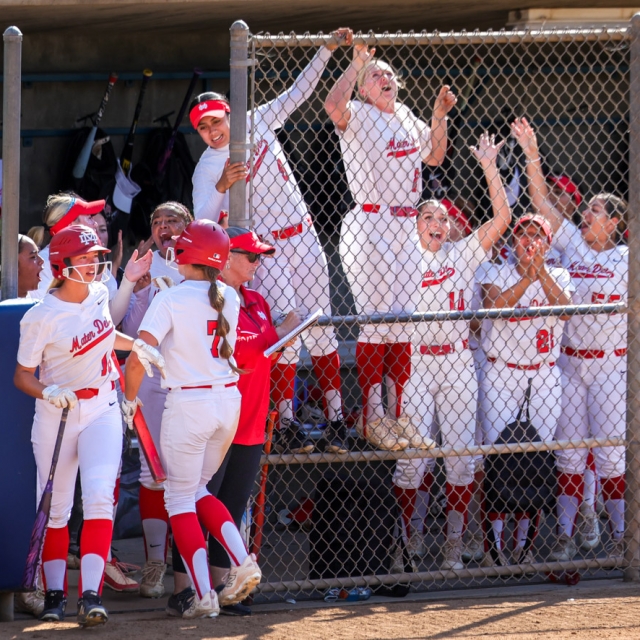 Mater Dei players celebrate a big play with Allyson Schmida on deck