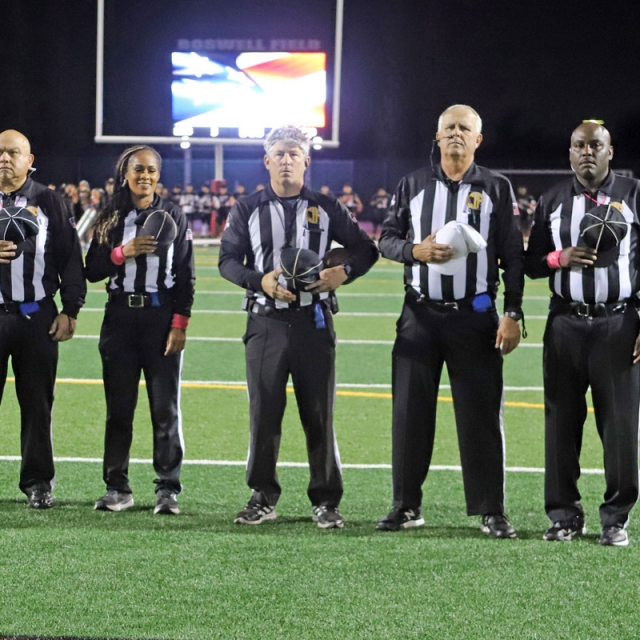 Members of the referee crew look on as the national anthem is being played.